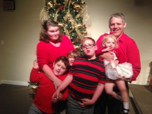 A family of six--two adults and four children of various ages--dressed in complimentary color in front of a Christmas tree. The photo is blurry because it was taken while the adults were attempting to wrestle four not very cooperative children into some semblence of order. It's a terrible photo. 